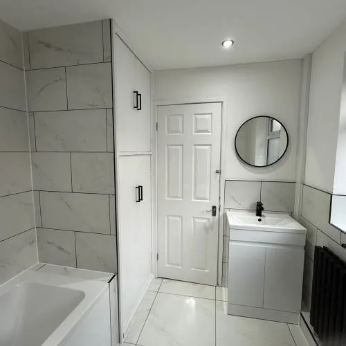 Bathroom with bath, round mirror and built-in storage cupboard