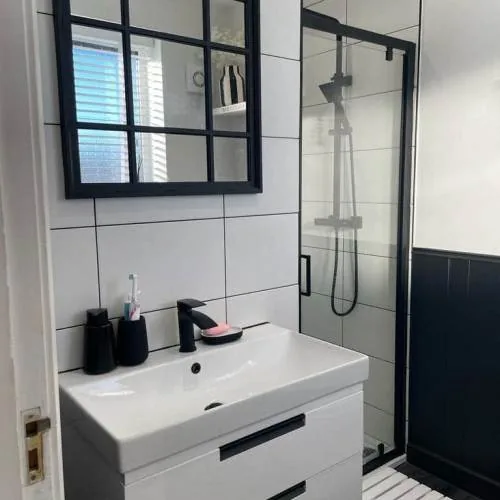 Bathroom with black framed mirror, white vanity unit and black framed shower