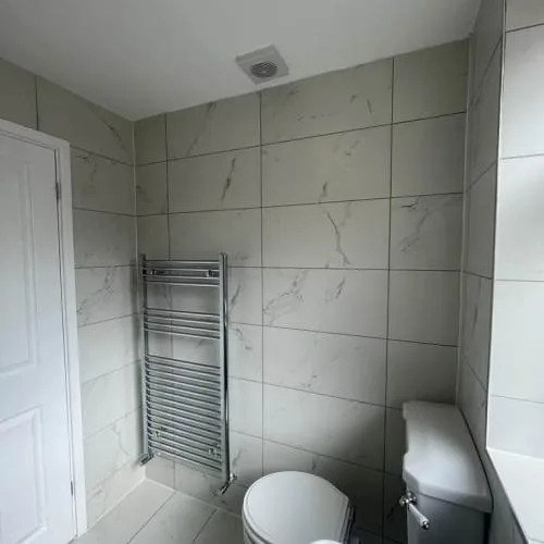 Bathroom with marble-effect tiles and chrome towel rail