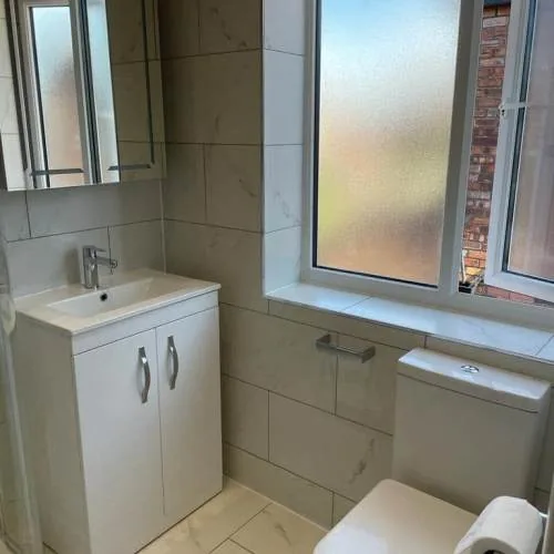 Bathroom with white vanity unit and marble-effect tiles