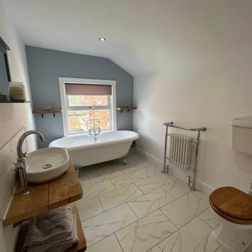 Freestanding roll-top bath beneath a window in a Warrington bathroom