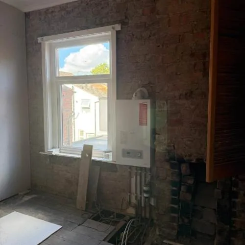 Kitchen stripped out ready for renovation, showing boiler and pipework