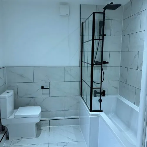 Shower bath with black framed screen and marble-effect tiles
