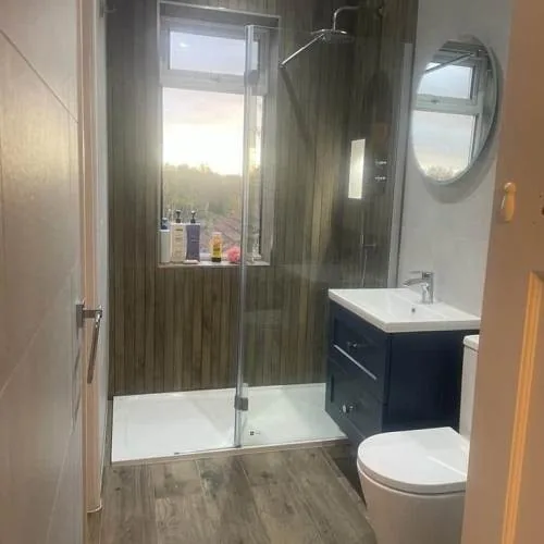 Shower room with walk-in shower, wood-effect wall panels and navy vanity