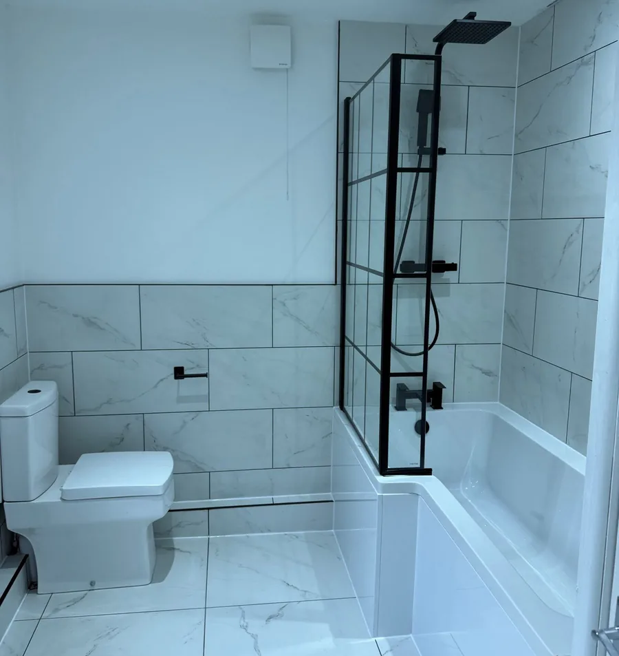 Shower bath with black framed screen and marble-effect tiles fitted by our plumber in Warrington